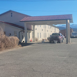 Exterior of San Luis Hotel Colorado with covered parking area and parked vehicles under a clear blue sky
